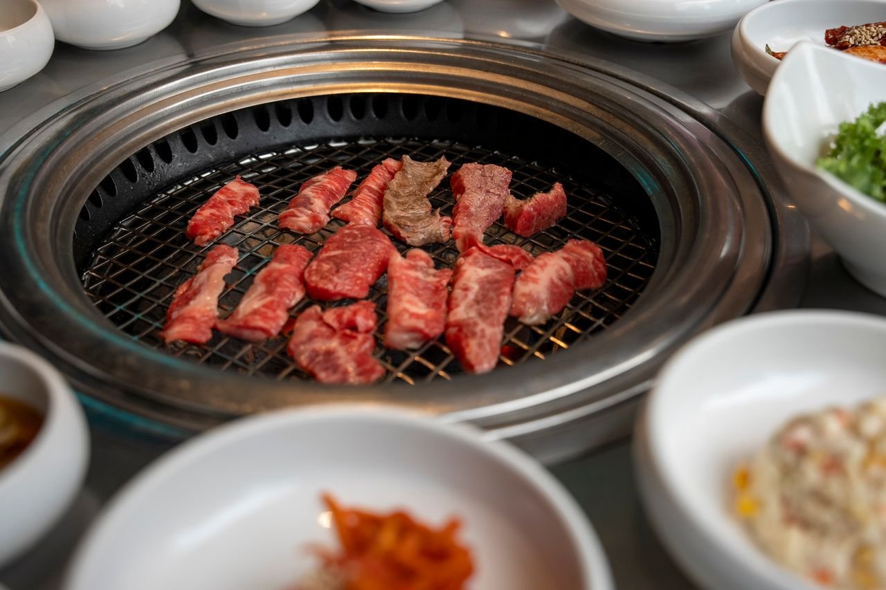 Mastering the First Impression: Your intriguing post title goes here Delicious cuts of beef cooking on a traditional Korean BBQ in Seoul, South Korea.