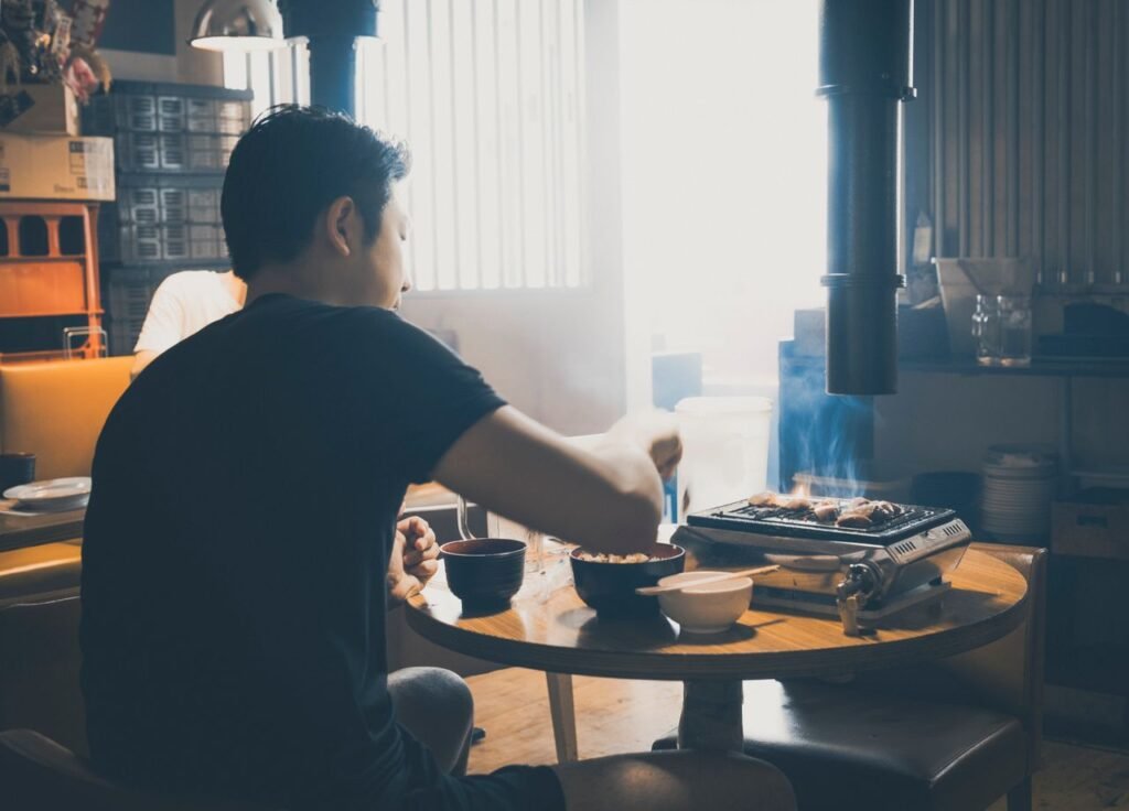 Man grilling meat indoors at a Japanese restaurant in Tokyo, Japan.