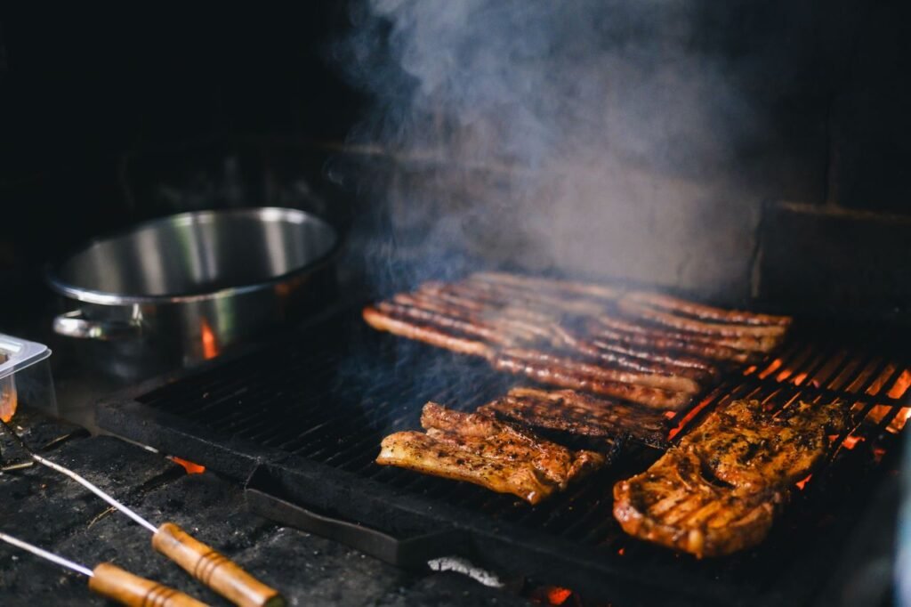 Close-up of grilled steaks sizzling on a smoky barbecue grill.